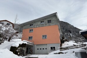 Un immeuble à plusieurs étages, doté d’un toit plat, d’un garage et surplombant un paysage enneigé.