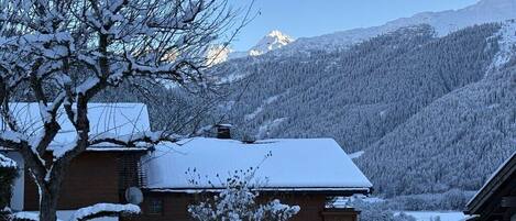 A snow-covered mountain landscape with a house in the foreground.