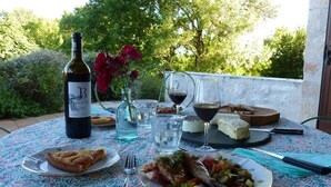 A table set outdoors with a bottle of wine, glasses, a plate of food, and a vase with flowers. - Pechingorp Guest Room - Tilleul - Shared Pool, Terrace, and Wi-Fi (Le Verdier)