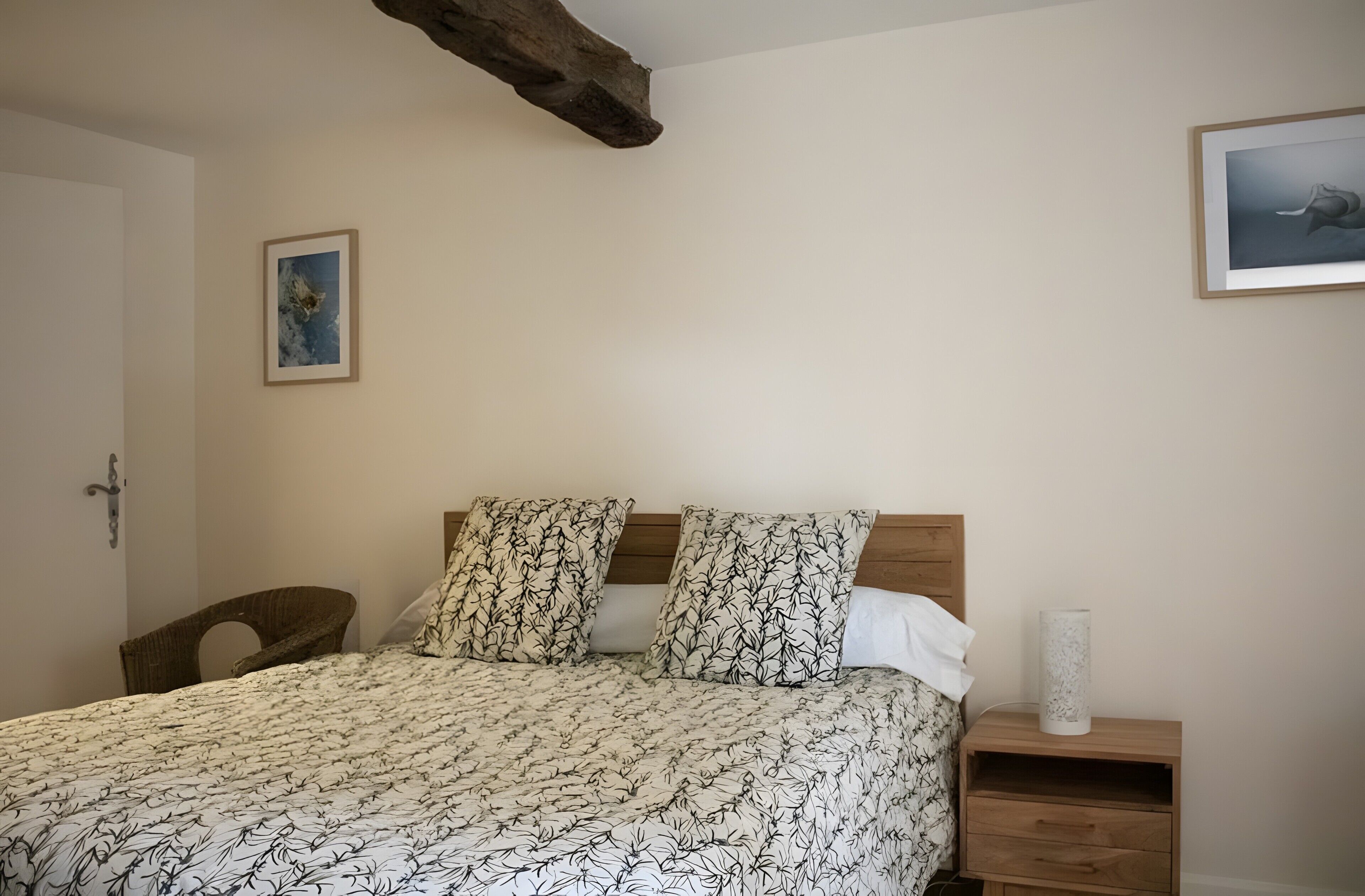 Une chambre à coucher avec un lit, deux oreillers, une table de chevet, une chaise et une porte.