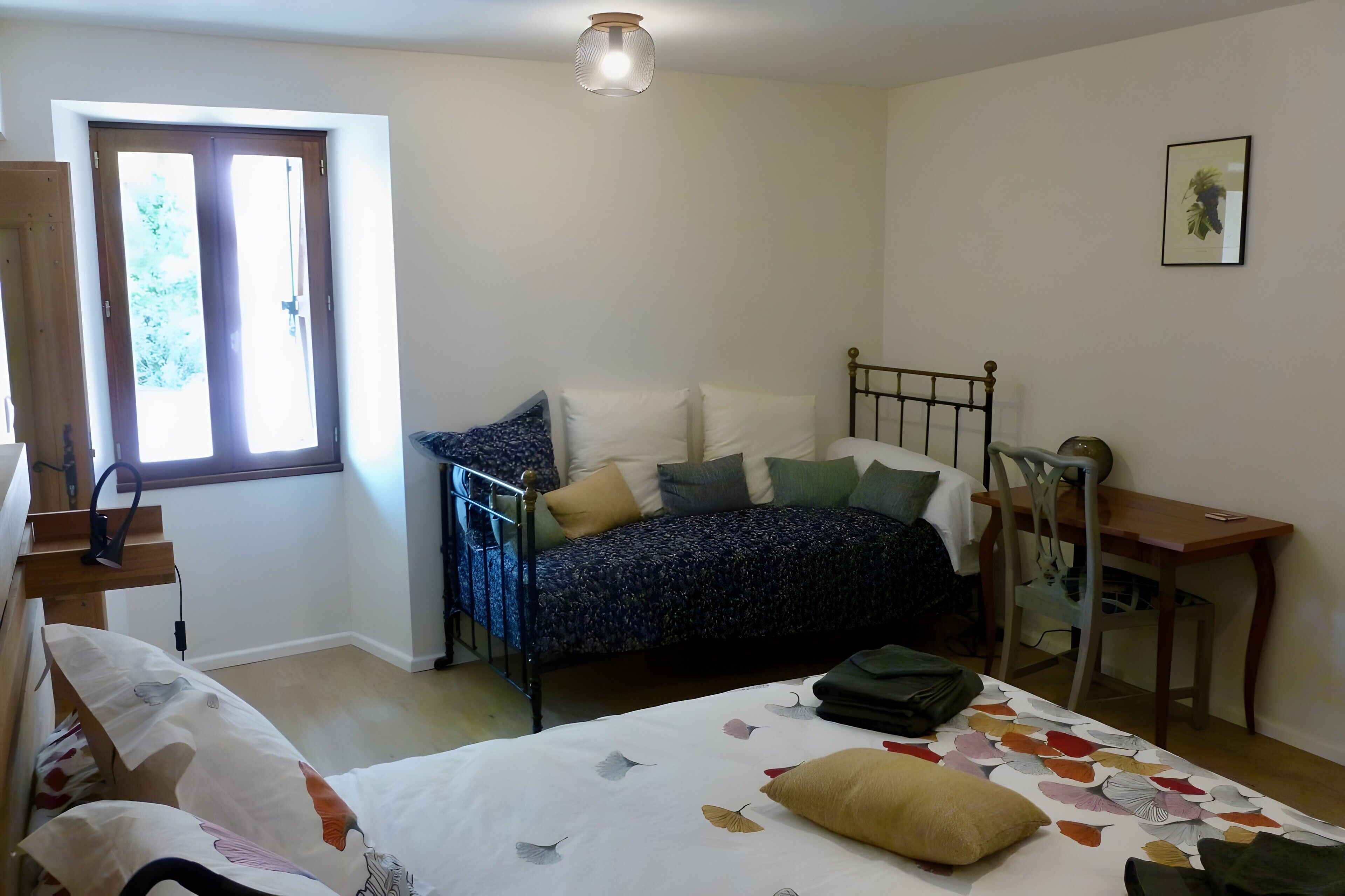 Een slaapkamer met een bed, een bureau, een stoel en een raam.