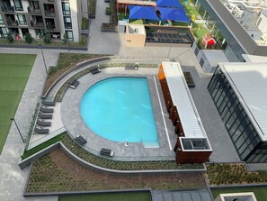 A swimming pool with a curved edge, surrounded by a walkway with seating areas. - Executive Twin King Ensuites Apartment - M-city Shopping center in Clayton, 3168 (Clayton)