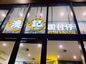 Ein Restaurant mit großen Fenstern und einem Schild, das den Hashtag #HKFOODIE enthält.