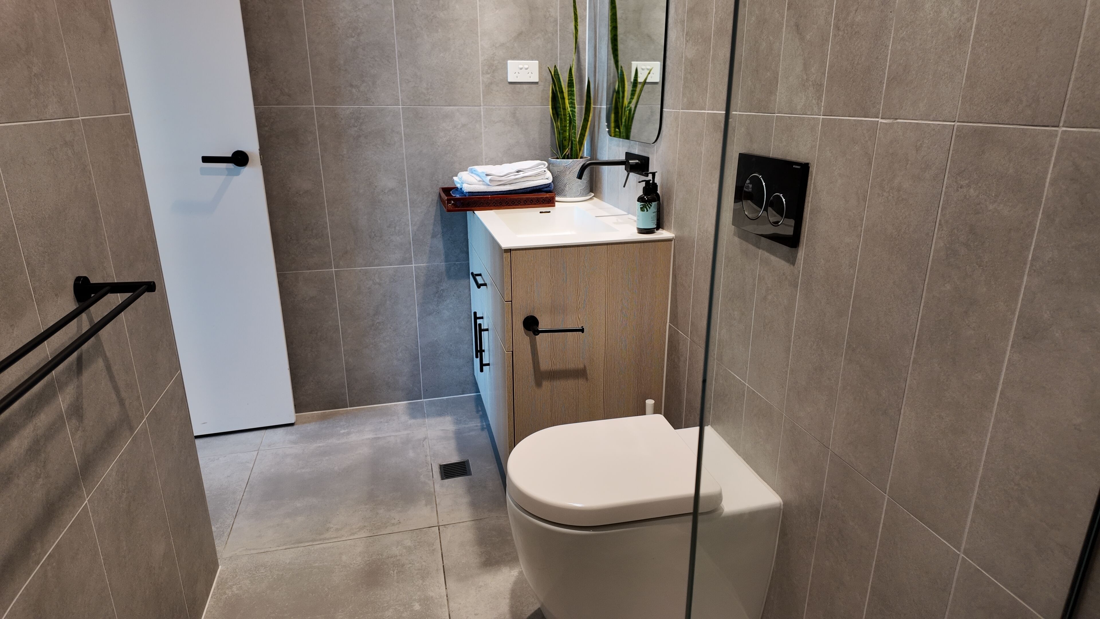A modern bathroom with a toilet, sink, and mirror.