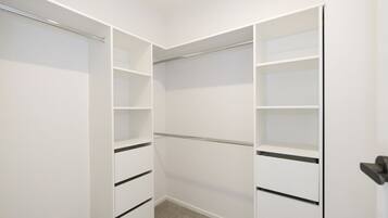 Un vestidor amplio con puertas abiertas, que muestra varias estanterías y cajones.