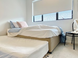 A bedroom with a bed, a chair, and a window with blinds.