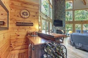 Un interior de madera con una zona de bar, una estantería para vinos y una chimenea de piedra.