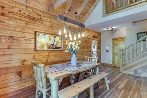A wooden dining area with a table, benches, and a hanging light fixture. - Dahlonega Wine Country Cabin w/ Hot Tub! (Dahlonega)