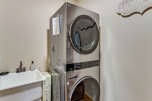 A stacked washer and dryer unit with a white sink and a soap dispenser on the countertop. - Dahlonega Wine Country Cabin w/ Hot Tub! (Dahlonega)