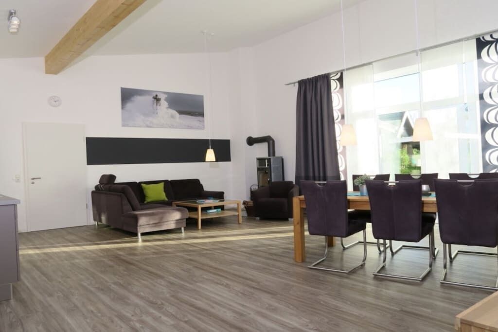 A modern living room with a sofa, coffee table, and dining area with chairs.