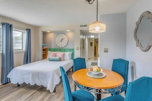 Ein Schlafzimmer mit einem Bett, einem runden Tisch mit Stühlen, einer Wanduhr und einer Hängelampe.