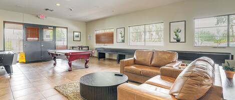 Un área de lounge con mesa de billar, sofás de cuero y mesa de ping pong.
