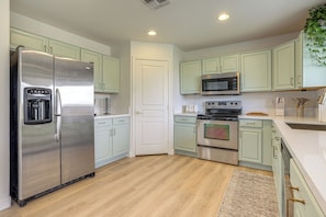A kitchen with light green cabinets, stainless steel appliances, and a wooden floor. - Golf View, Pool Access! Updated Queen Creek Home (Queen Creek)