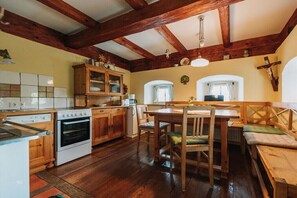 A kitchen with wooden cabinets, a stove, and a dining area with benches. - Holiday apartment with 1 bedroom (St. Johann)