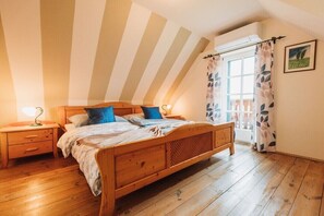 Ein Schlafzimmer mit einem hölzernen Bett, einem Nachttisch, einem Fenster mit Vorhängen und einem Bild an der Wand.