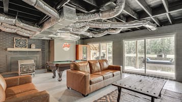 A spacious room with a pool table, leather sofa, and a fireplace.