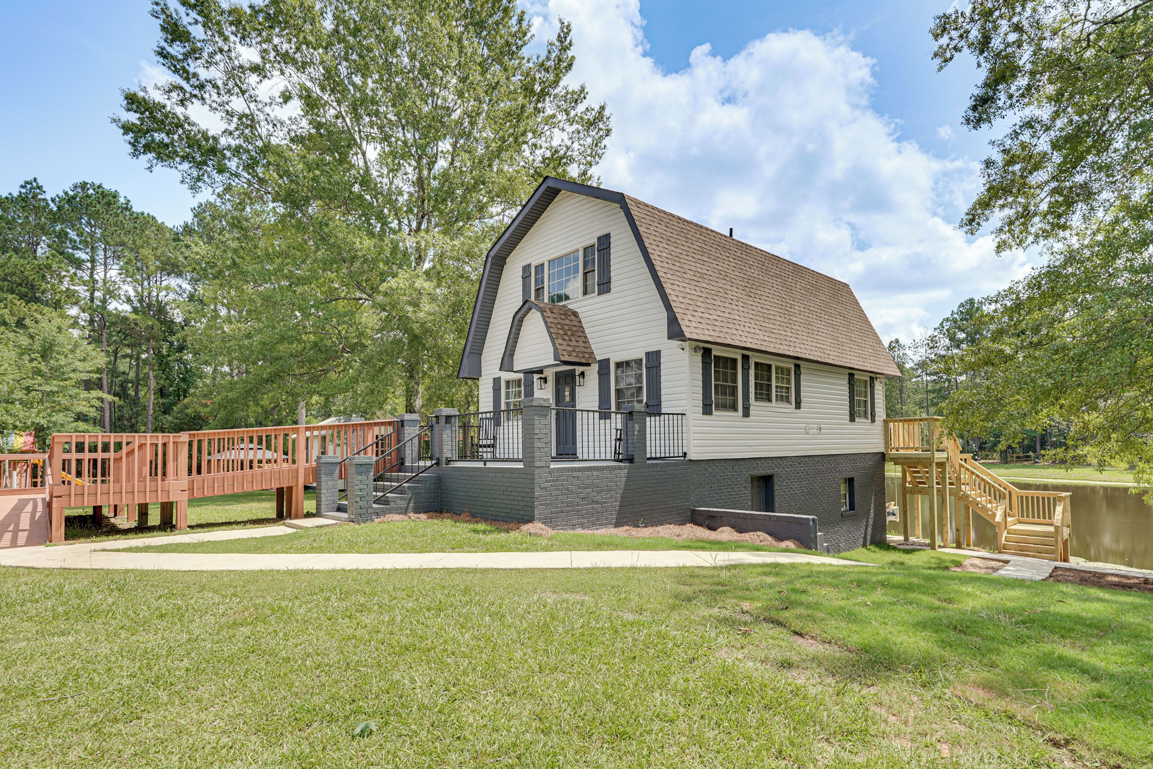 A two-story house with a sloped roof, a front porch, and a small deck.