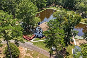 A house with a deck and a pond in a wooded area. - Waterfront Retreat | Fishing, Hot Tub & Sauna (Harlem)
