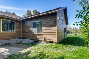Una casa a due piani in legno con vialetto sterrato e giardino con prato.