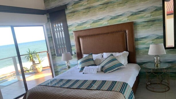A hotel room with a large bed, a view of the sea, and a balcony. - The Dolphines Hive View (iLembe District Municipality)