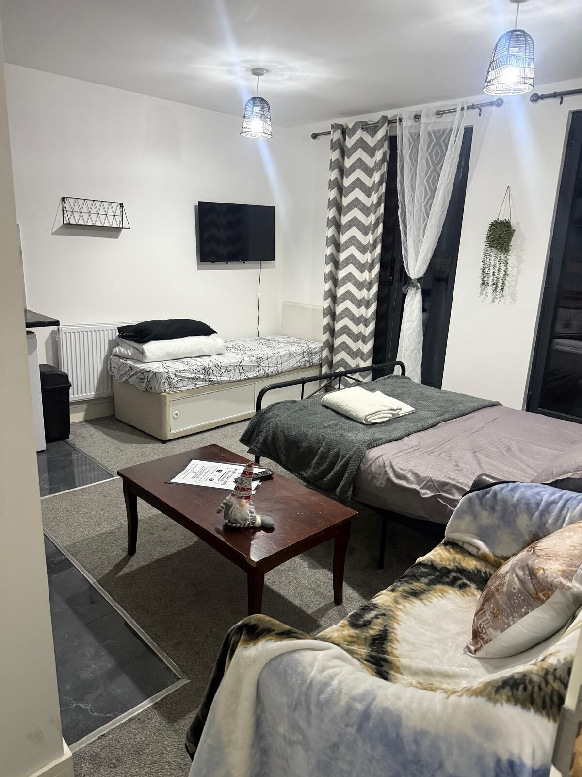 Ein Schlafzimmer mit einem Bett, einem Sofa, einem kleinen Tisch, einem Fernseher und einer Heizung.