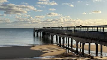 Eine Pier, die sich in ruhiges Wasser erstreckt, mit einem wolkenlosen Himmel darüber.