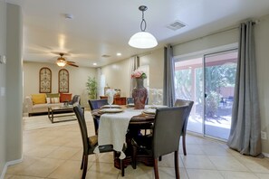 A dining area with a table set for four, chairs, a ceiling fan, and a view through a large sliding glass door. - Extended Stay w/ Pool Access, Near Queen Creek (San Tan Valley)