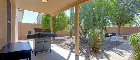 An outdoor patio with a barbecue grill, seating area, and cacti.