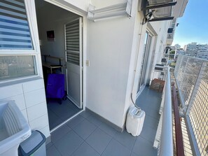 Un balcón con vistas a la ciudad, una puerta cerrada y una mesa azul.