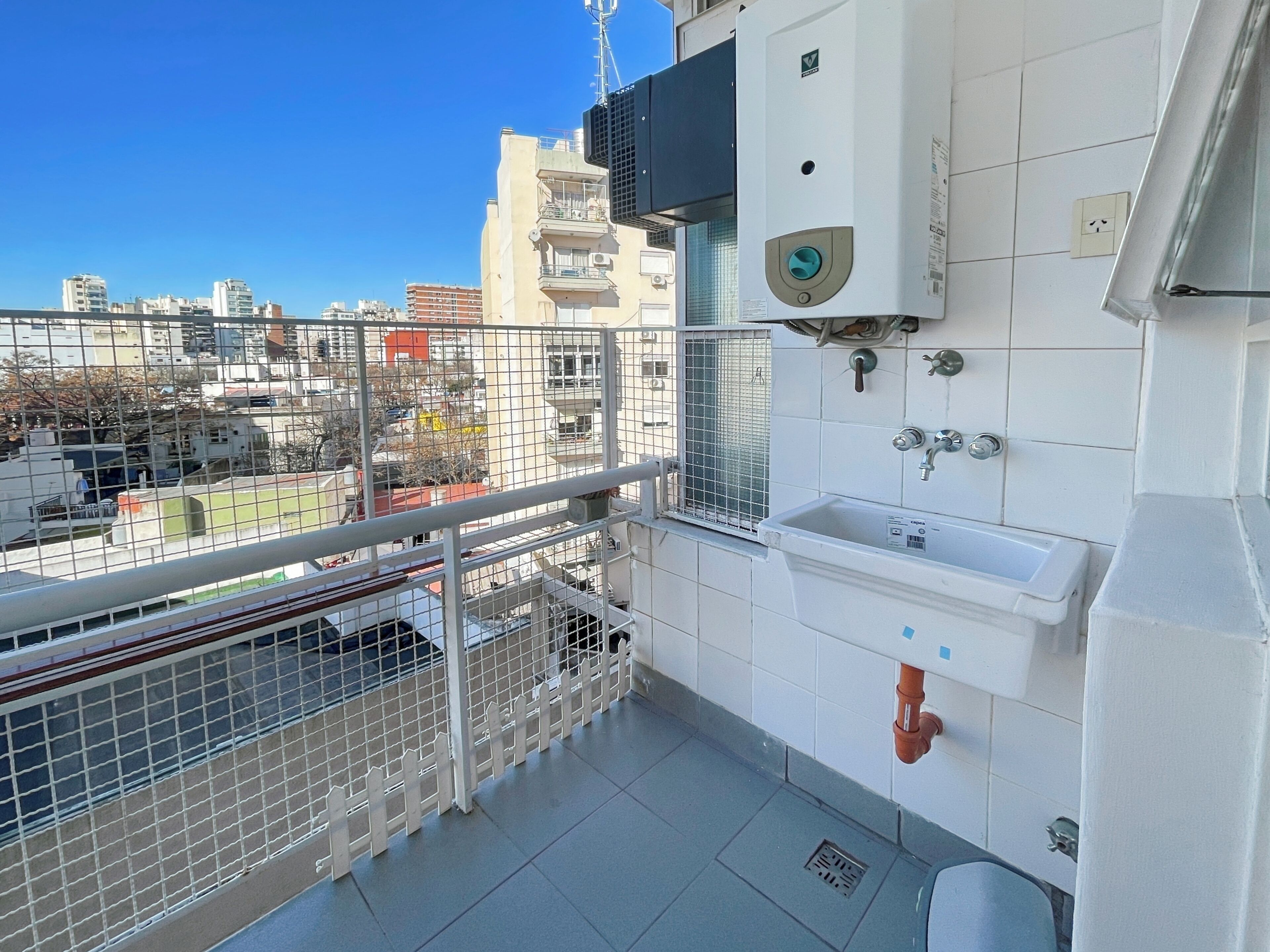 A balcony with a metal railing, a white sink, and a water heater on the wall.
