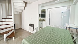 Ein Zimmer mit einem Bett, einem Esstisch, einer Küchenzeile und einer Treppe.