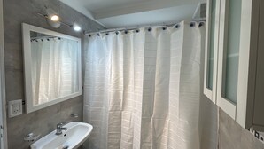 Ein Badezimmer mit einem weißen Waschbecken, einem Spiegel und einer Duschvorhang.