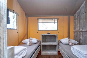 A room with two single beds, a small table, and a window.