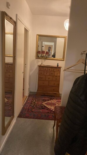 A hallway with a wooden dresser, a mirror, and a patterned rug. - Cozy 1-Bedroom Apartment in Central Kungsholmen, Stockholm (Kungsholmen)
