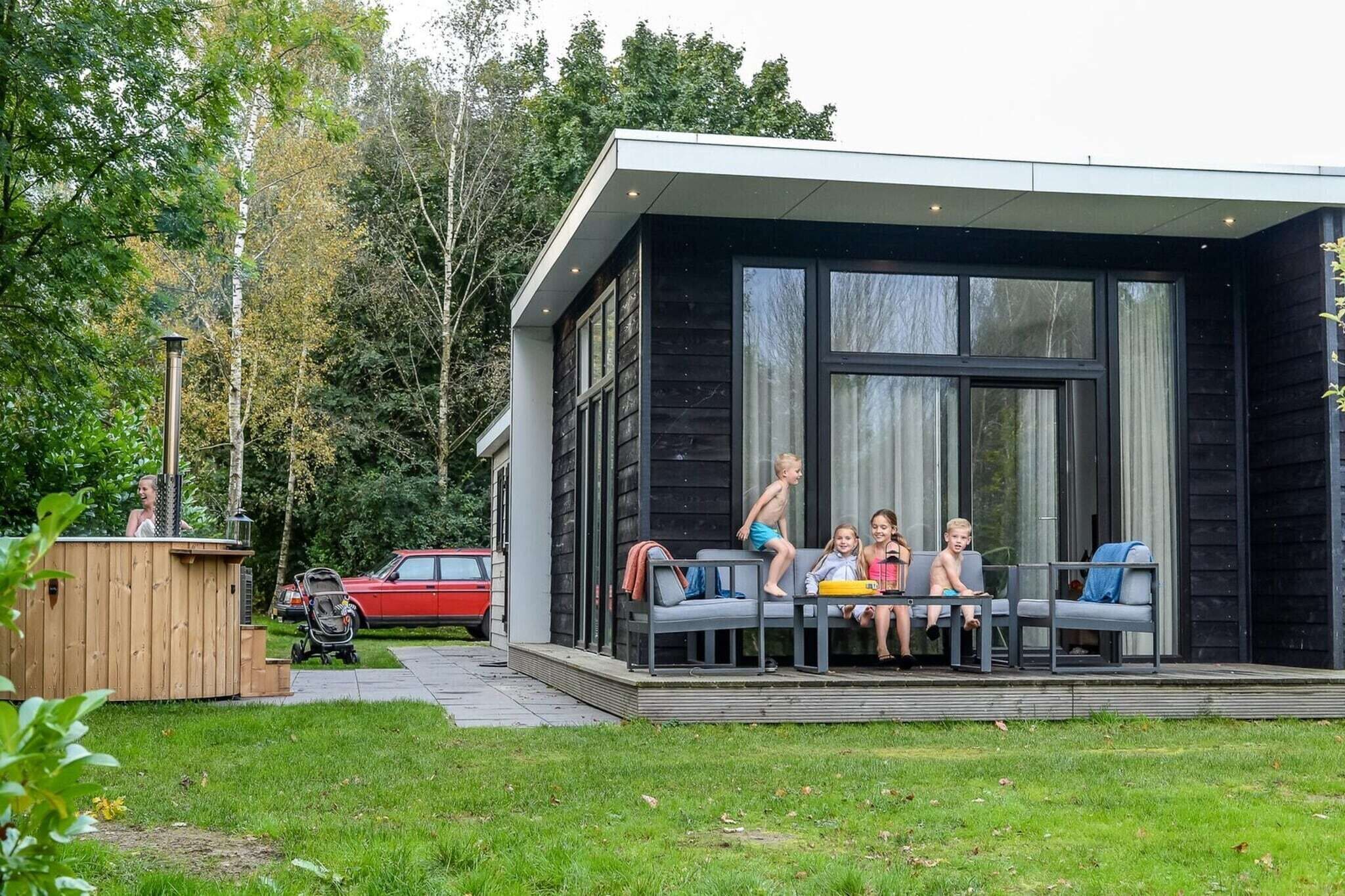 Una casa moderna con un portico dove siedono dei bambini.