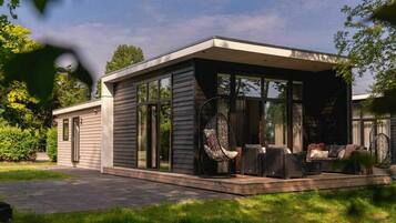 A modern house with a covered patio area, large windows, and outdoor furniture.