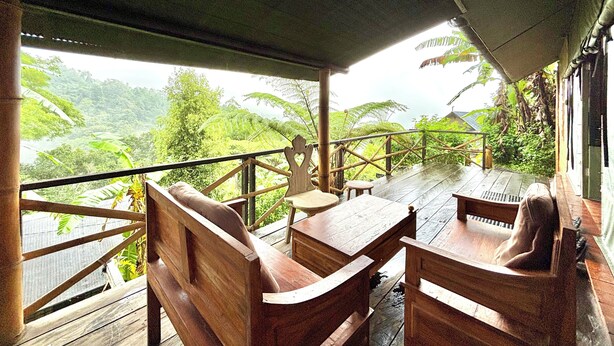 A wooden deck with a table and benches overlooking a lush landscape.