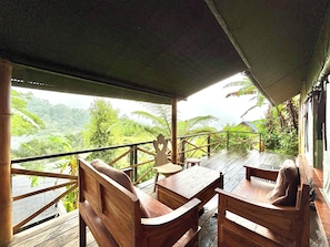 A wooden deck with a table and benches overlooking a lush landscape.