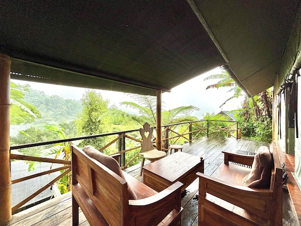A wooden deck with a table and benches overlooking a lush landscape.