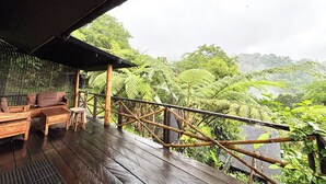 A wooden deck with a bamboo railing overlooking a lush forest.