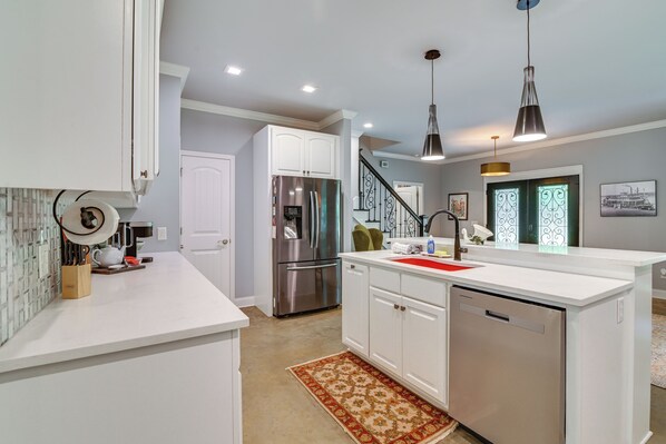 A modern kitchen with white cabinetry, stainless steel appliances, and a red island.