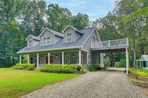 A two-story house with a covered porch and a gravel driveway.