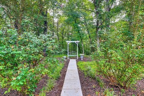 A pathway leading to a white pergola in a lush garden setting.