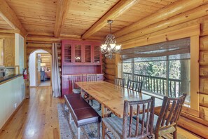 A log cabin interior with a dining area, wooden walls, and a large window. - All-Season Family Cabin w/ Forest Views in Truckee (Truckee)