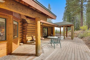 A log cabin with a covered patio area, outdoor seating, and a view of the surrounding forest. - All-Season Family Cabin w/ Forest Views in Truckee (Truckee)