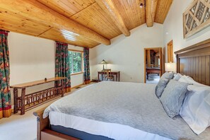 A bedroom with a large bed, wooden ceiling, and a view of the outdoors. - All-Season Family Cabin w/ Forest Views in Truckee (Truckee)