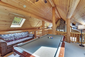 Un intérieur en bois avec une table de billard, un banc rembourré et une cheminée en pierre.