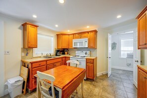 A compact kitchen with wooden cabinets, a white stove, and a sink. - Prime Naples Park Location! Beachy Duplex (Naples)