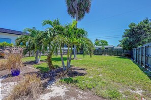 A residential backyard with palm trees, a wooden fence, and a clear blue sky. - Prime Naples Park Location! Beachy Duplex (Naples)