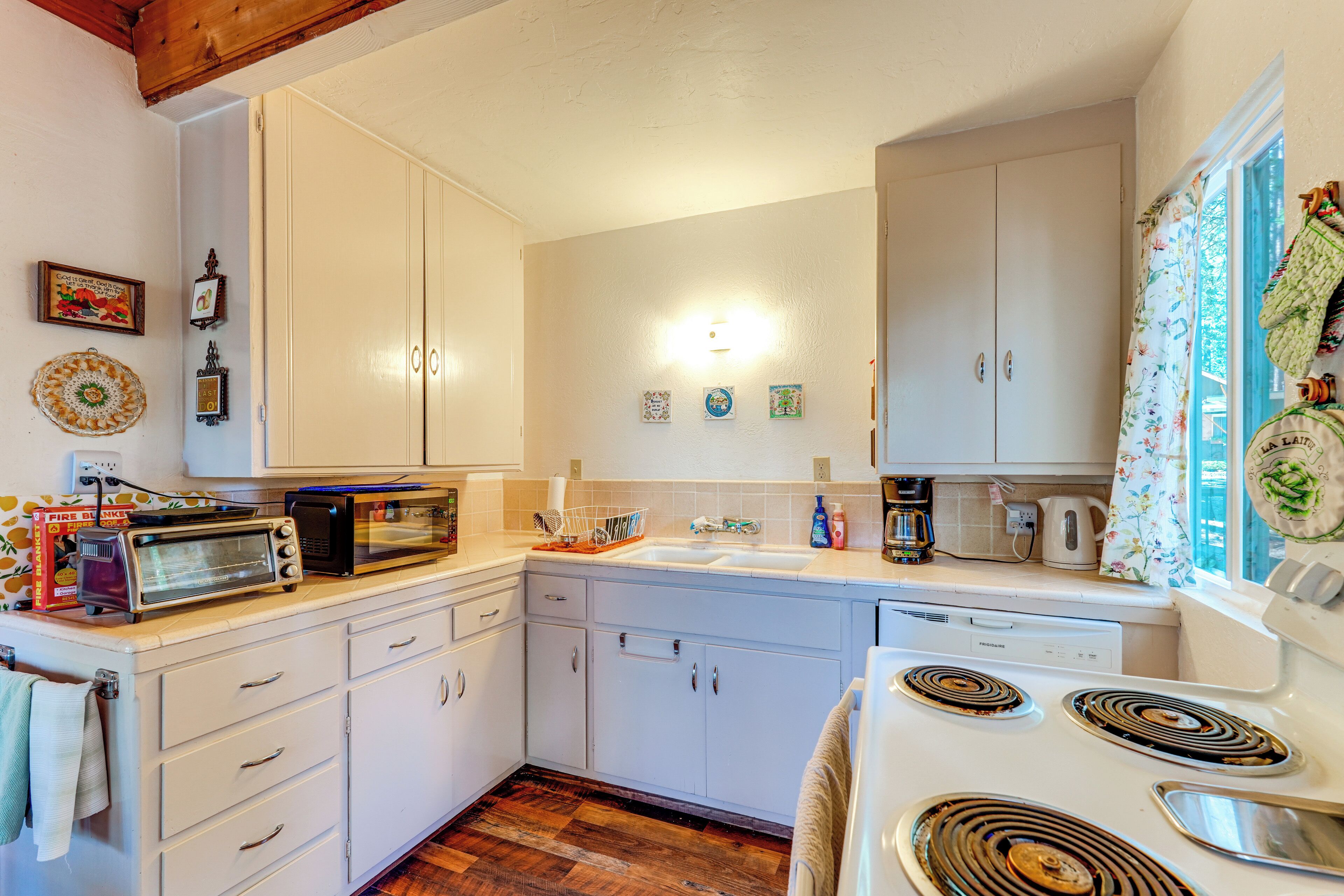 A compact kitchen with white cabinets, a microwave, a toaster, and a stove.